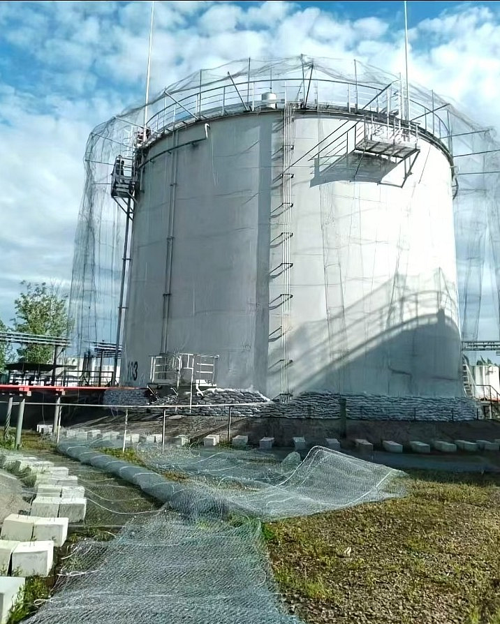 Gabion barriers and protective mesh around an industrial storage tank