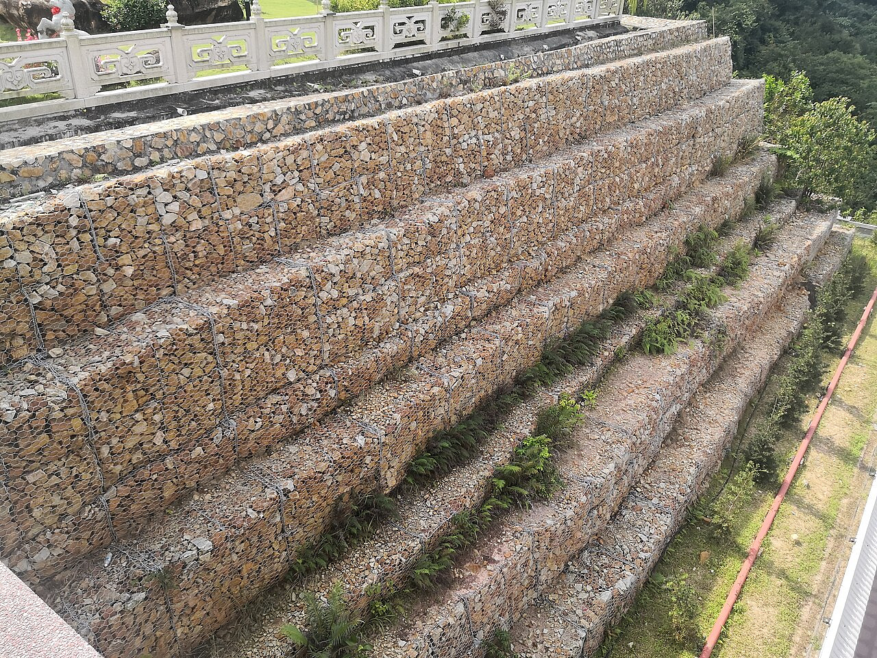 Gabion retaining wall supporting a sloped embankment