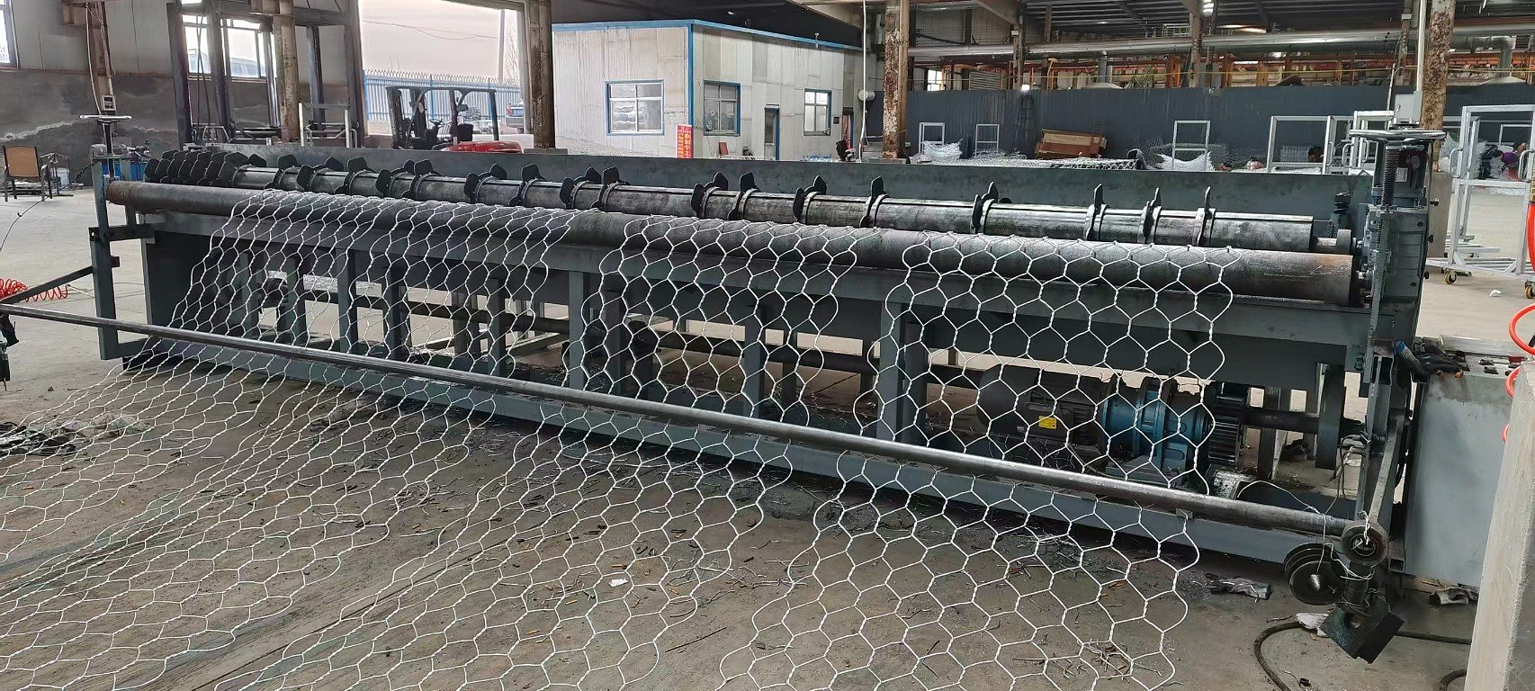 Front view of a gabion mesh cutting machine with a full mesh panel spread across the table